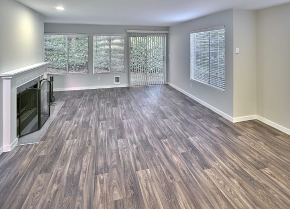 an empty living room with a fireplace and wooden floors at Edmonds Gateway, Washington