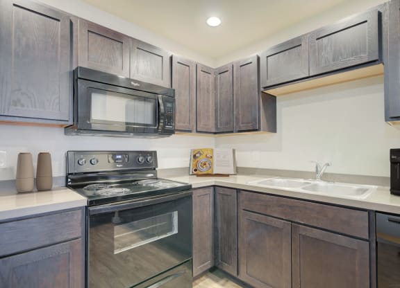 a kitchen with black appliances and wooden cabinets at Madison Park, Montana, 59718