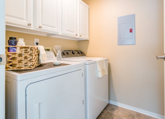 a washer and dryer in a laundry room with white cabinets  at Springfield, Renton, WA