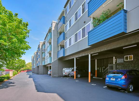 Apartments with carports, access to the leading office to the right, and mailboxes and trees on the left.