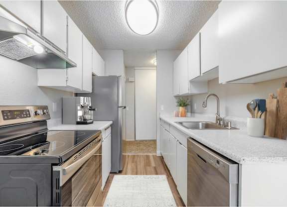 Modern kitchen at Peak 88 Apartments in Renton, WA with stainless steel appliances and wood-style flooring