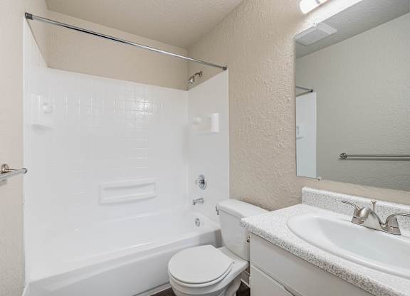 Clean bathroom with a standard toilet, sink, and white finishes in a Peak 88 Apartment home in Renton, WA.