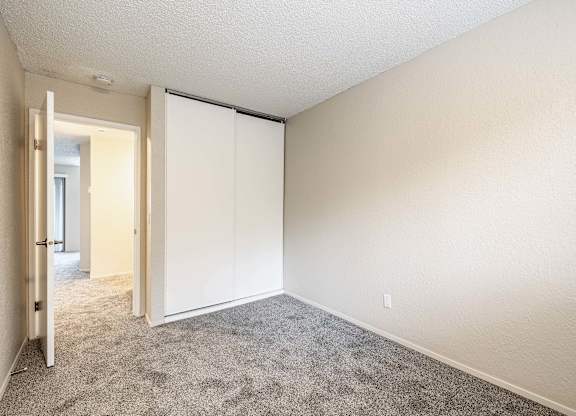 Bedroom with soft carpet and a sliding closet door inside a Peak 88 two-bedroom apartment in Renton, WA.