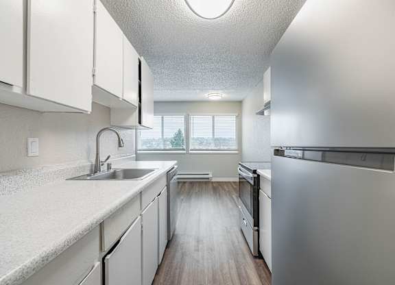 Updated kitchen with white cabinetry and a stainless-steel refrigerator in a Peak 88 Apartment home in Renton, WA.