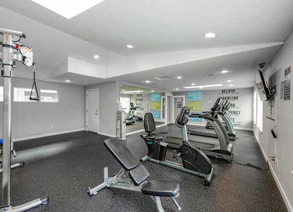 A gym with a row of treadmills and a weight machine.