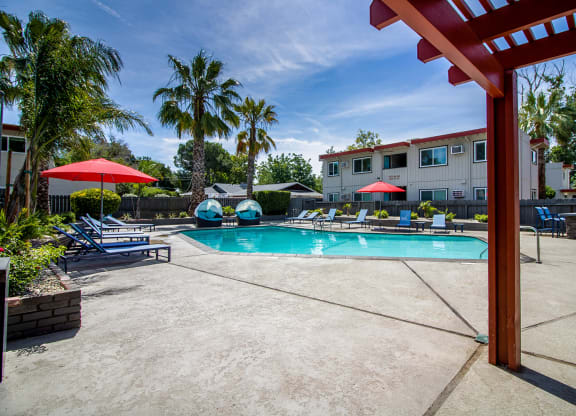 Resort style pool with lounge chairs, umbrellas, covered seating and BBQ at Woodland Village Apartments , California, 95695