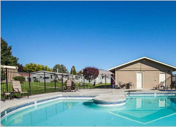 Swimming pool and pool house with lounge chairs and trees in the distance at Park View Apartments, Wenatchee Washington