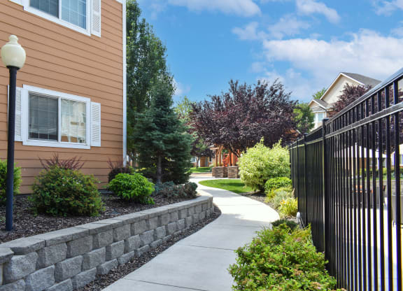 Walkway through apartment community in West Richland, WA surrounded by green plants.