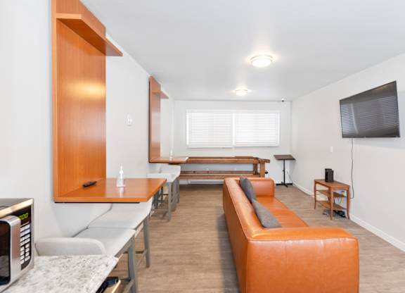 A modern resident lounge with a long orange sofa and a television on the wall at our Billings apartments in MT.