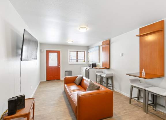 A living room with a couch, a television, and a bar area at Rock Creek Apartments in Billings, MT.