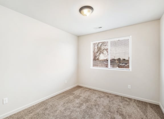 Clean, bright bedroom with taupe carpet, white walls and a large window on one wall. at Pine Tree Park, Washington