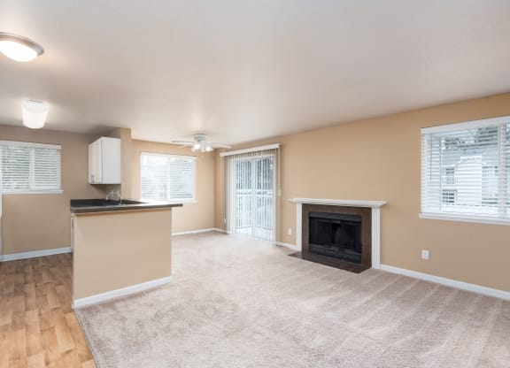an empty living room with a fireplace and a kitchen
