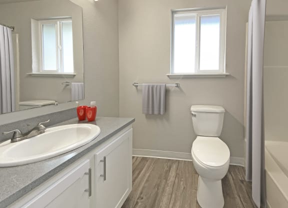 Full bathroom, vanity sink, large mirror, towel rack, toilet with window above, shower, and gray shower curtain.at Quilceda Gardens, Marysville, WA