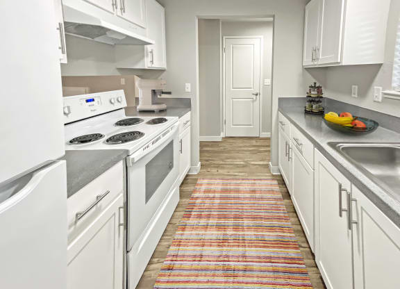 Double galley kitchen, wood-like floors, full-size fridge, top and bottom cabinets, oven, stovetop, and sink.at Quilceda Gardens, Marysville, 98270