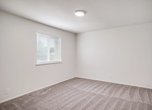 an empty room with carpet and a window