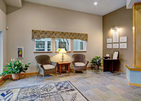 A waiting room with a rug and chairs.