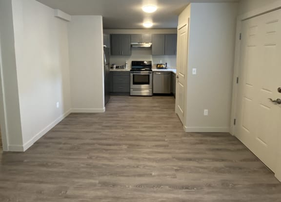 a view of a kitchen and a hallway with wood flooring at The Lakes in Moses Lake, WA.