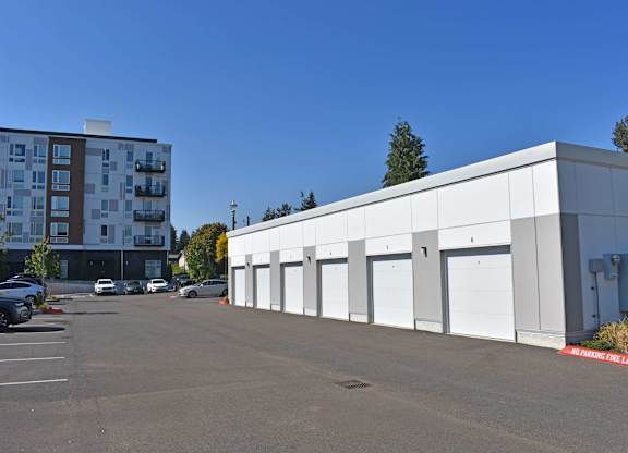 A parking lot with a white building and a red and white striped barrier.