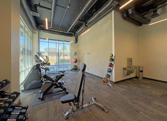 A gym with a row of treadmills and a weight rack at The Duo Apartments in University Place, WA.