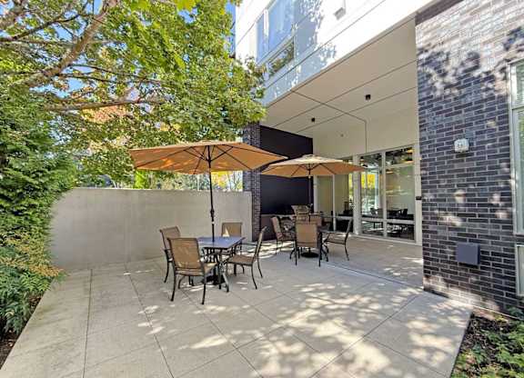 A patio with a table and chairs under an umbrella at The Duo Apartments in University Place, WA.