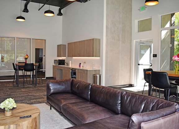 A brown leather couch in a room with a table and chairs at the Duo Apartments in University Place.