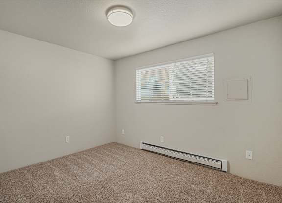 1 bedroom apartment with large window, wall AC unit and plush carpet at The Lakes Apartments in Moses Lake Washington