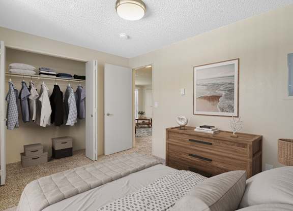 Spacious bedroom with queen bed, wood dresser, and full closet at The Lakes Apartments in Moses Lake