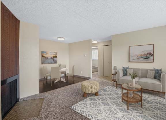 Bright living room with neutral couch, accent chairs, and coffee table in an 850 sq ft 2 bed apartment