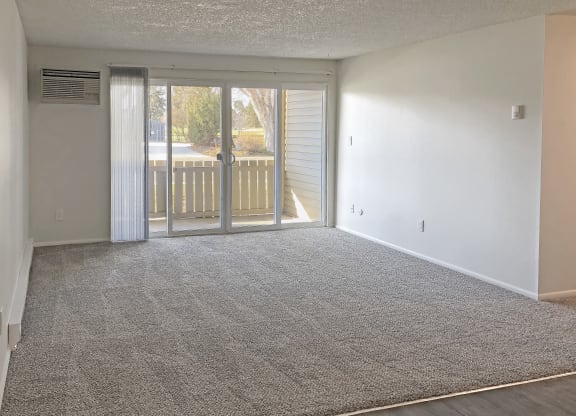 Spacious living room with gray carpet and large sliding glass doors to private patio in Boise, ID at Talavera.