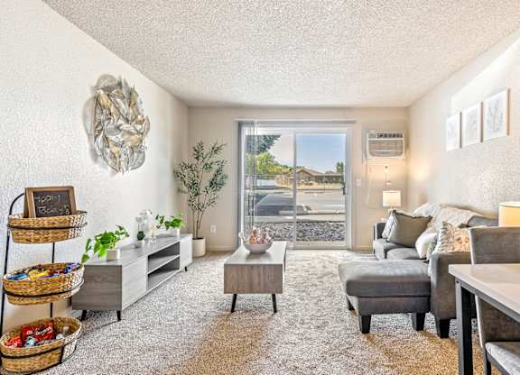 A living room with a grey couch and a white wall t Wildflower Apartments in Kennewick, WA.