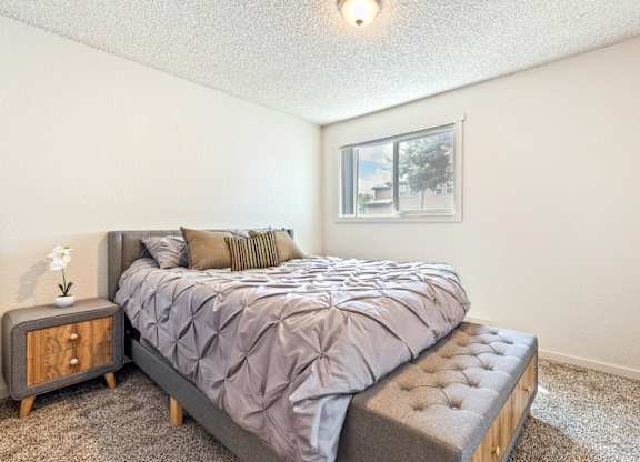 A bedroom with a bed, nightstand, and window at Wildflower, Kennewick, WA 99336.