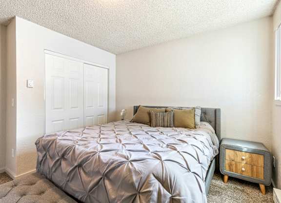 A bedroom with a bed, nightstand, and a door at Wildflower in Kennewick, WA..