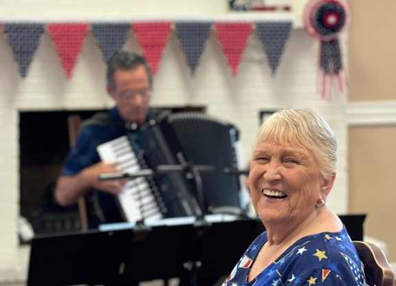 A woman is sitting in front of a piano at Lodi Commons Senior Living, Lodi, CA, 95240