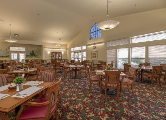 a large dining room with tables and chairs and windows at Hilltop Commons Senior Living, Grass Valley California