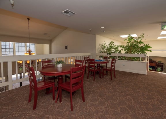 a dining room with a table and chairs and a balcony at Hilltop Commons Senior Living, Grass Valley, CA