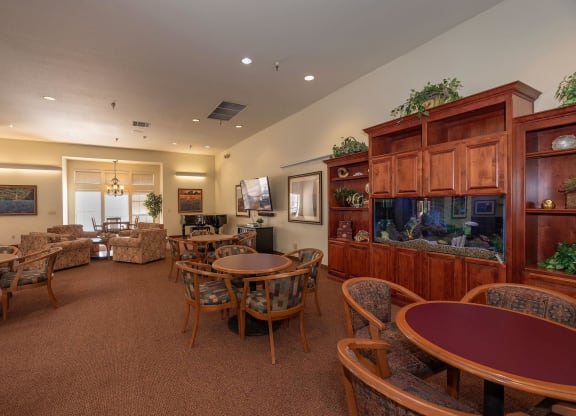 a living room with tables and chairs and a fish tank at Hilltop Commons Senior Living, California