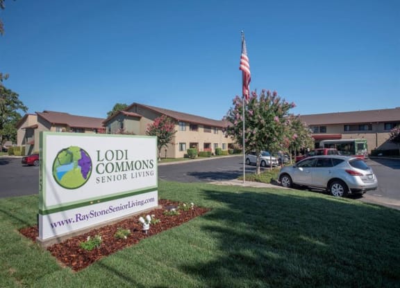 Front entrance to Lodi Commons with sign and grassy knoll at Lodi Commons Senior Living, Lodi, CA 95240