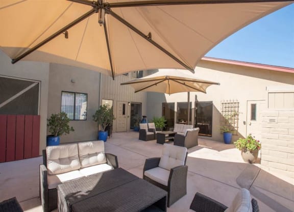 Outdoor patio and courtyard area with chairs and umbrellas at Lodi Commons Senior Living, Lodi, CA