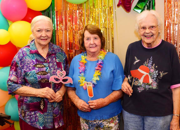three women standing in front of balloons at a party at River Commons Senior Living, Redding, CA 96002