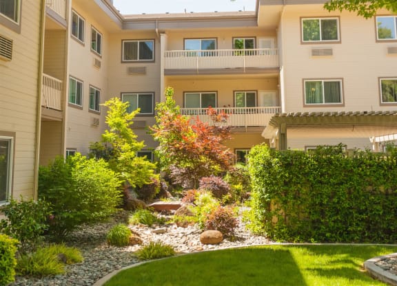 a landscaped yard in front of an apartment building at River Commons Senior Living, Redding, 96002