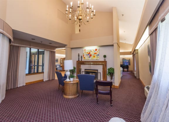 a large lobby with chairs and a table and a fireplace at River Commons Senior Living, Redding, CA 96002