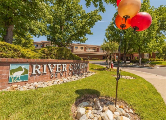 a sign for river country seed with balloons in front of a building at River Commons Senior Living, California, 96002