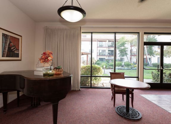 a living room with a piano and a table at Roseville Commons Senior Living, Roseville California