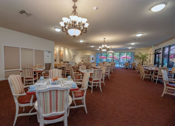 a dining room with tables and chairs and a chandelier at Roseville Commons Senior Living, Roseville, CA 95678