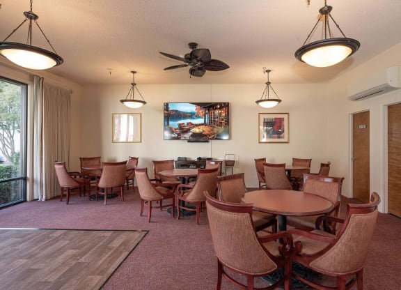 a dining room with tables and chairs and a tv at Roseville Commons Senior Living, Roseville