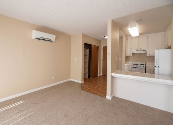 an empty living room with a kitchen in the background at Roseville Commons Senior Living, Roseville