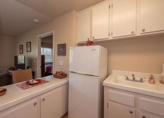 a kitchen with white cabinets and a white refrigerator at Roseville Commons Senior Living, Roseville, CA 95678