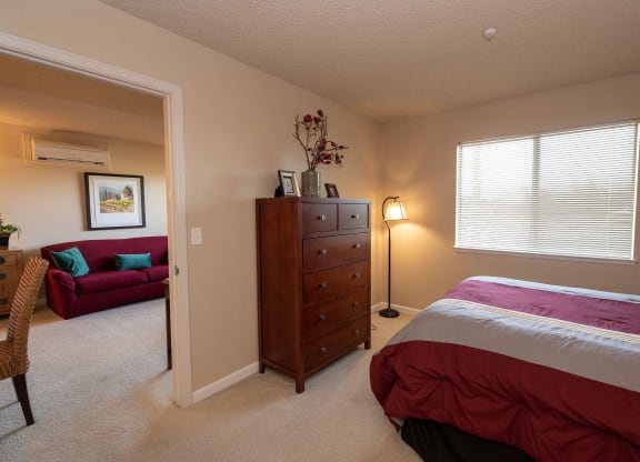 a bedroom with a bed and a living room with a couch at Roseville Commons Senior Living, California