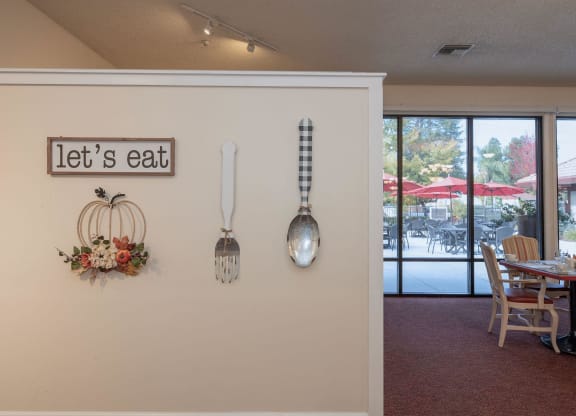 a dining room with utensils hanging on the wall and a table and chairs at Roseville Commons Senior Living, Roseville California