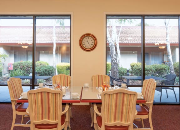 a dining room table with chairs and a clock on the wall at Roseville Commons Senior Living, Roseville, CA